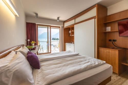 a bedroom with a large bed and a balcony at Ambienthotel Spiaggia in Malcesine