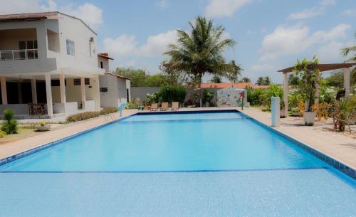a large blue swimming pool in front of a house at Pousada Itarema Residence in Itarema