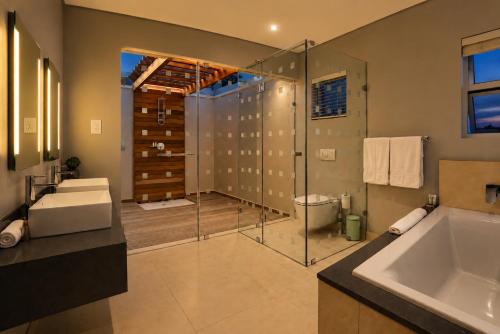 a bathroom with a shower and a tub and a sink at Vetho House Villa Ballito in Ballito