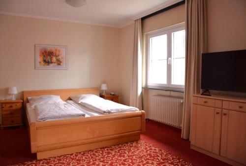a bedroom with a bed and a flat screen tv at Hotel Stadt Lübeck in Timmendorfer Strand