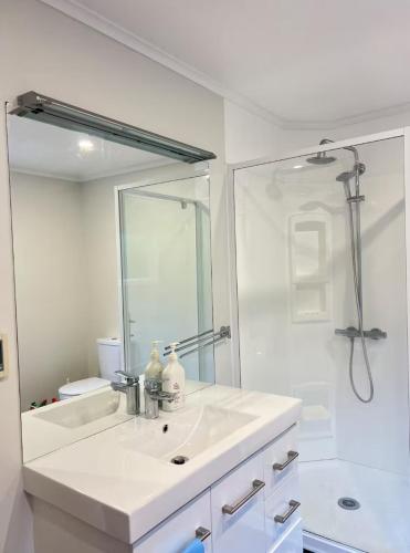 a white bathroom with a sink and a shower at Campvan Stay in Auckland