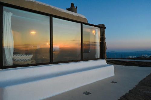 a view of a sunset through windows on a building at ⋆ 5BR Oceanside View Near Lighthouse- Pharos VM ⋆ in Mikonos