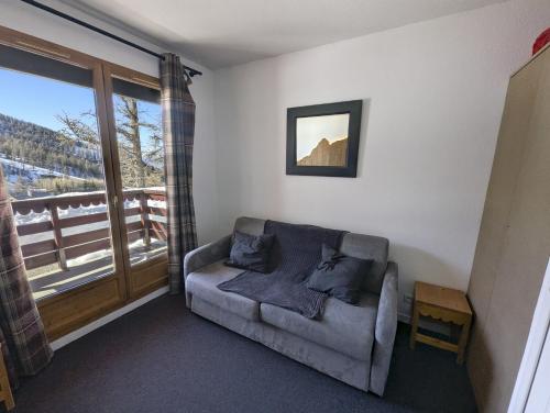 a living room with a couch and a large window at Le Nid Rouge Risoul Balcony & View Ski 100 m in Risoul
