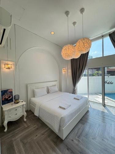 a bedroom with a large bed and a chandelier at Nadda Pool Villa Ranong in Ban Bang Rin (1)