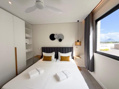 a bedroom with a large white bed with yellow pillows at Asmara Residence 2 Bedroom Apartment by LOV Mauritius, Beach Access in Petite Case Noyale
