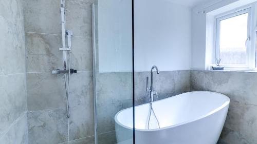 a bathroom with a tub and a glass shower at Spacious and Modern Durham home in Gilesgate