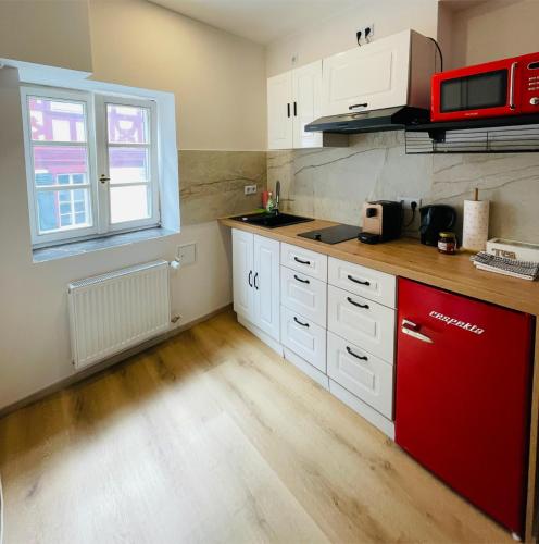 a kitchen with white cabinets and a red refrigerator at Ferienwohnung am Entenplatz in Eltville