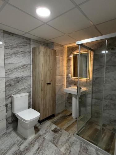 a bathroom with a toilet and a glass shower at Skopje Riverfront Modern Apartment in Skopje