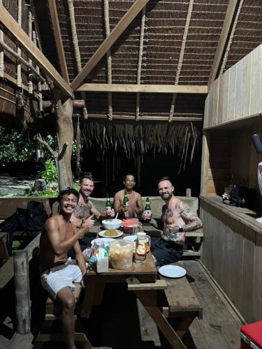 a group of men sitting at a picnic table at Mentawai Tribe Experience & Private Beach Camp in Pulau Masilo