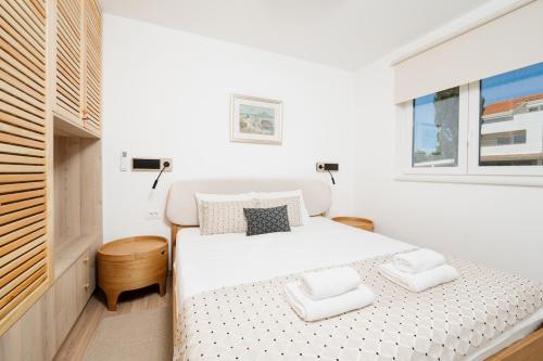 a white bedroom with a white bed and a window at Residence Giardino in Ugljan