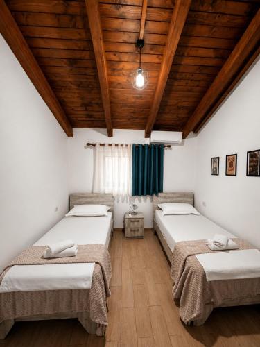 three beds in a room with a wooden ceiling at Js House Shkoder 2 in Shkodër