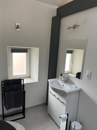 a white bathroom with a sink and a mirror at Week end à Spa in Spa