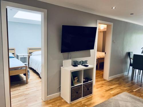 a room with a bed and a television on a wall at Whiteleys Cottages 2 bedroom in Renton