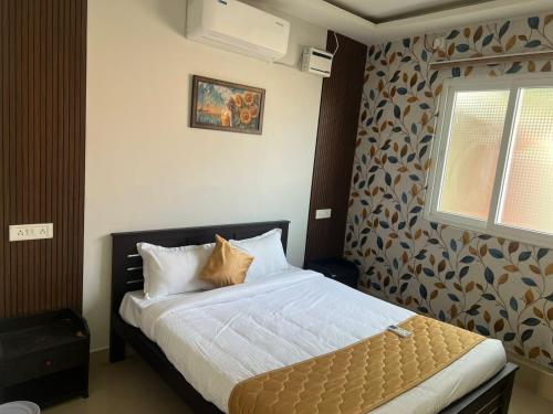 a bedroom with a bed with white sheets and a window at Aerodon resort in Chennai