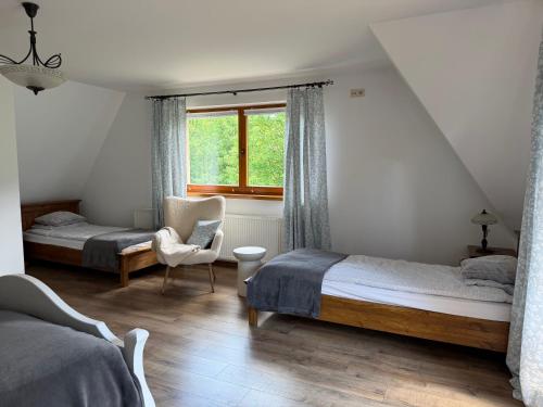 a bedroom with two beds and a chair and a window at Apartament u SKOCZKA in Poronin