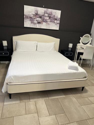 a bedroom with a bed with white sheets and a table at Tenuta Serena Apartments in Molfetta