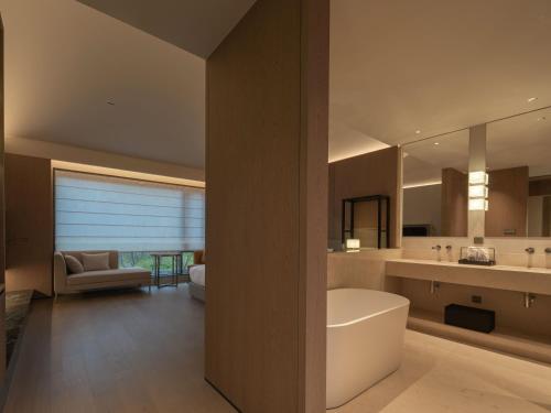 a bathroom with a tub and a sink and a mirror at Hayama Pagoda Villa in Taizhou