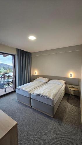 a bedroom with a large bed and a large window at Wellness penzión Predná Hora in Muráň
