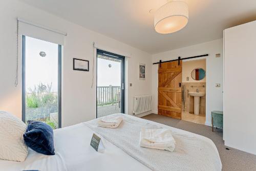 a bedroom with a white bed and a bathroom at Residence Number 5 - Luxury 2 Bed Ground Floor Apartment By Together Travel in Nefyn