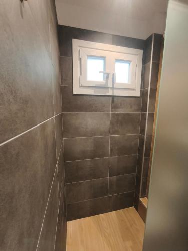 a bathroom with a window and a tiled wall at Skalopati Studios & Villa in Panormos Skopelos