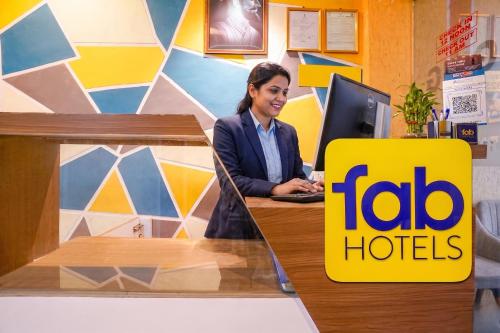 a woman sitting at a desk with a laptop at FabHotel Nilsa in Pālghar