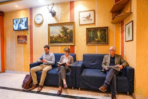 three men sitting on a couch in a waiting room at FabHotel Nilsa in Pālghar