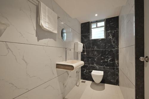 a white bathroom with a toilet and a window at II EMPYREAN STAYS II AURA VILLA II 3BHK II AC II LARGE POOL Il in Lonavala