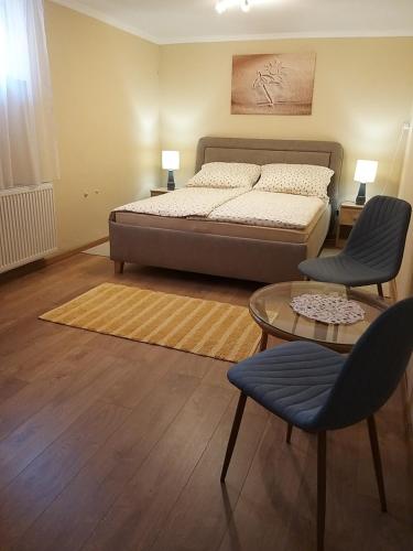 a bedroom with a bed and two chairs and a table at Magdaléna Vendégház in Esztergom
