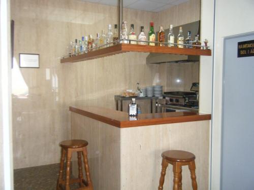 a kitchen with two stools and a bar with bottles at Hotel Costa San Antonio in Cullera