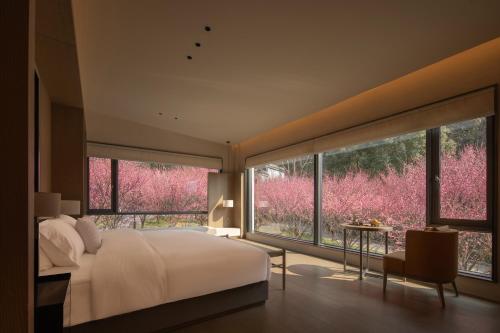 a bedroom with a large bed and large windows at Hayama Pagoda Villa in Taizhou
