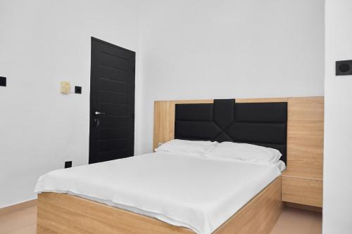 a bedroom with a large bed with a black headboard at IGBADUN House in Godomey