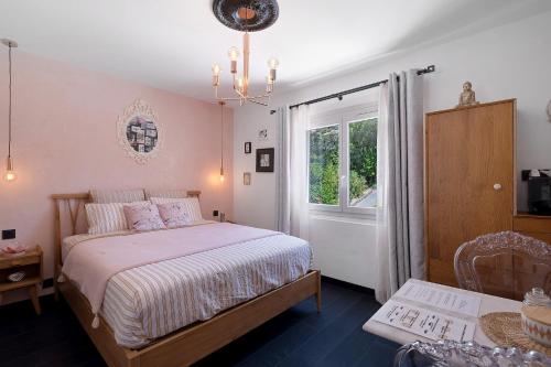 a bedroom with a bed and a window and a chandelier at Les Arbousiers in Saint-Raphaël