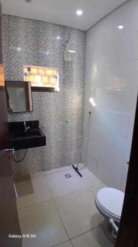 a bathroom with a toilet and a sink and a mirror at Casa de férias Pôr do Sol 4 in Bataguaçu