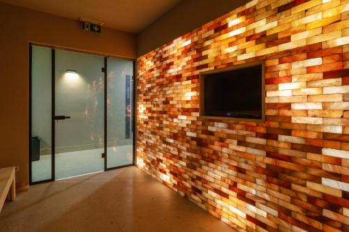 a room with a brick wall with a flat screen tv at Wellness penzión Predná Hora in Muráň