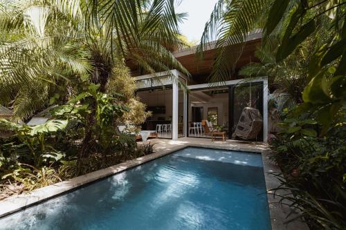 a swimming pool in front of a house with palm trees at Nalu Nosara Pool Villa Flor in Nosara