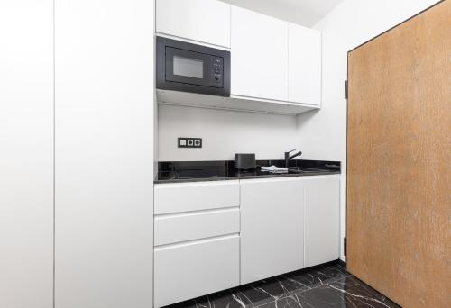 a kitchen with white cabinets and a microwave at Ferienwohnung 210 Salinenparc Design Budget Hotel in Erwitte