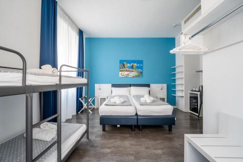a room with two bunk beds and a blue wall at Hotel Aurora & Appartamenti in Nago-Torbole