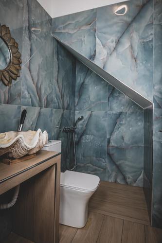 a bathroom with a toilet and a marble wall at Calliοpe's home in Skiathos