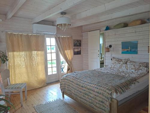 a bedroom with a bed and a large window at Zeltarasa in Avotkalni