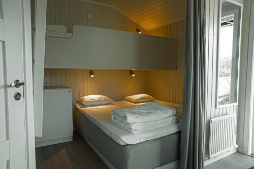 a bed in a small room with a window at Lisebergsbyns Stugor in Gothenburg