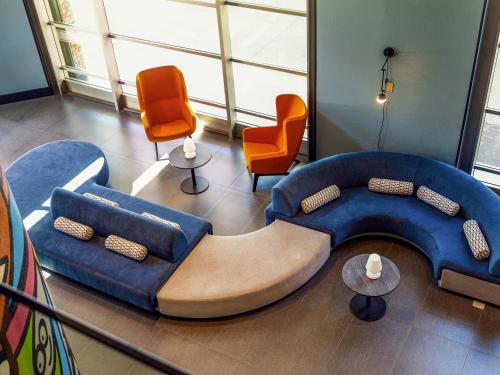 a living room with a blue couch and orange chairs at Novotel Santiago Las Condes in Santiago