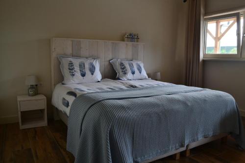 1 dormitorio con 1 cama con edredón blanco y ventana en B&B de Boerenzwaluw, en Harmelen