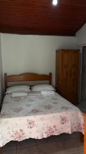 a bedroom with a bed with a wooden headboard and a cabinet at Suítes Dona Ilda in Pirenópolis