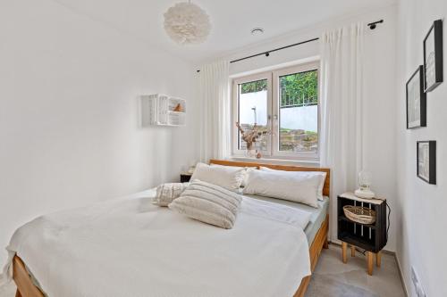 a white bedroom with a bed and a window at Appartment SPATZENNEST in Bietigheim-Bissingen
