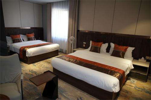 a hotel room with two beds and a chair at Happiness Hotel Ulaanbaatar in Ulaanbaatar