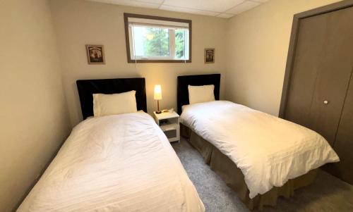 two beds in a small bedroom with a window at Bed & Breakfast Monarch in Canmore