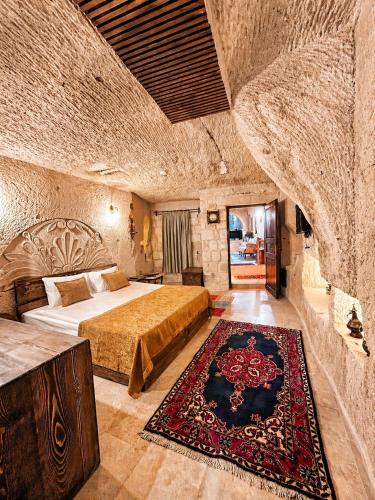 a bedroom with a large bed in a stone wall at Masar Cave Konak in Ortahisar