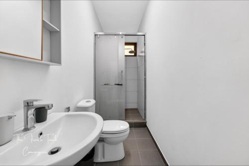 a white bathroom with a toilet and a sink at The Jacuzzi Escape in Flic-en-Flac
