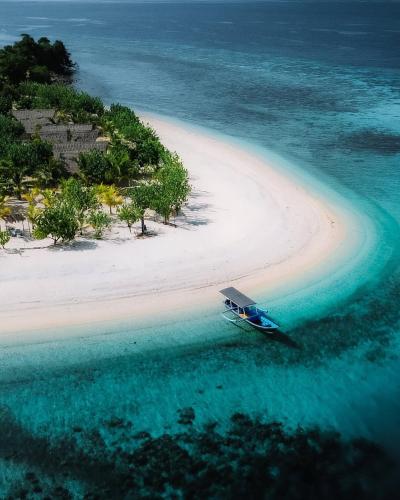 an island in the ocean with a boat in the water at Phinisi Private trip Komodo Island in Komodo Labuan Bajo Airport