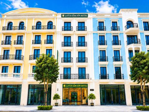 a large white building with trees in front of it at Lotus Sầm Sơn Hotel in Sầm Sơn